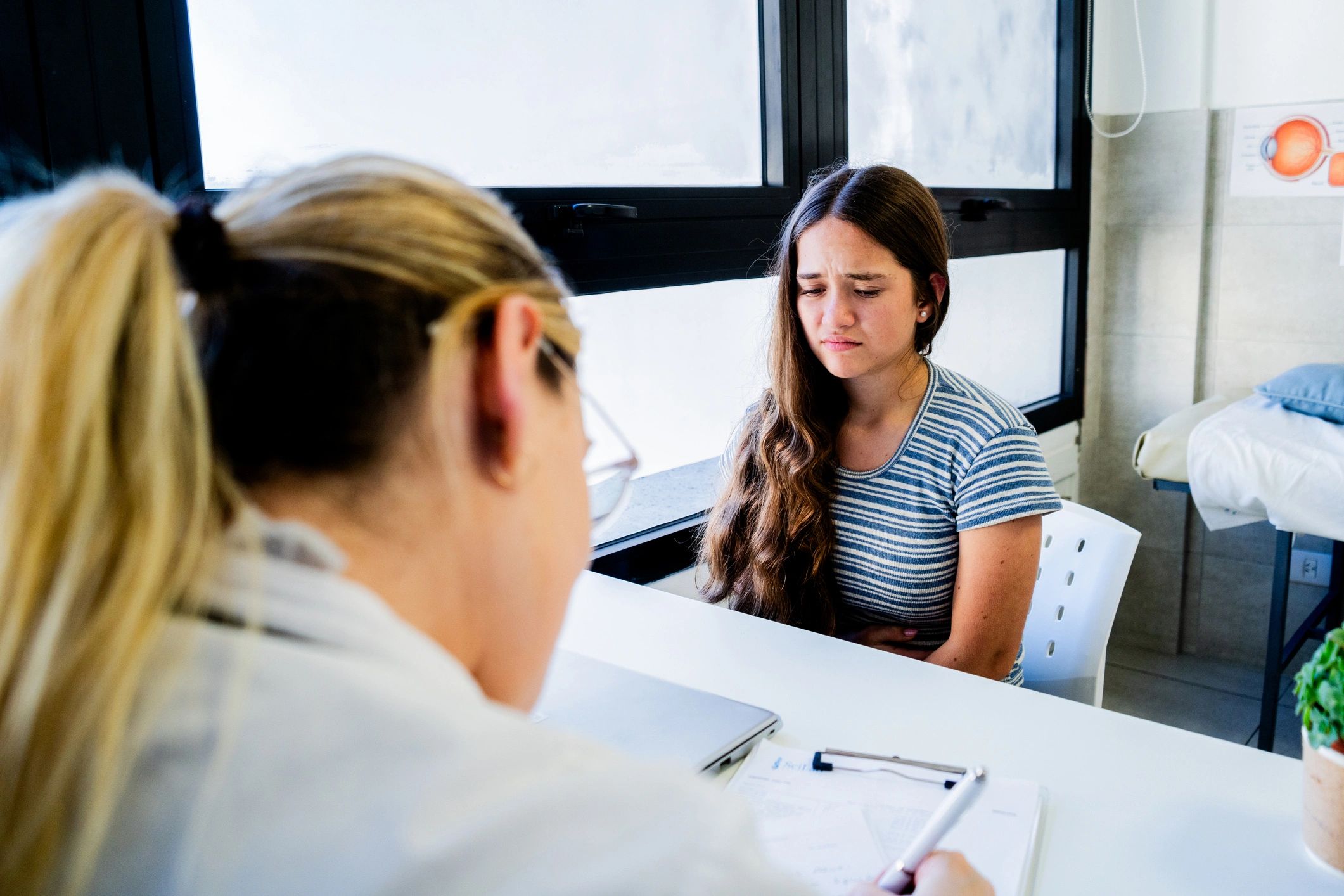 Adolescente conversando con médica en un entorno clínico