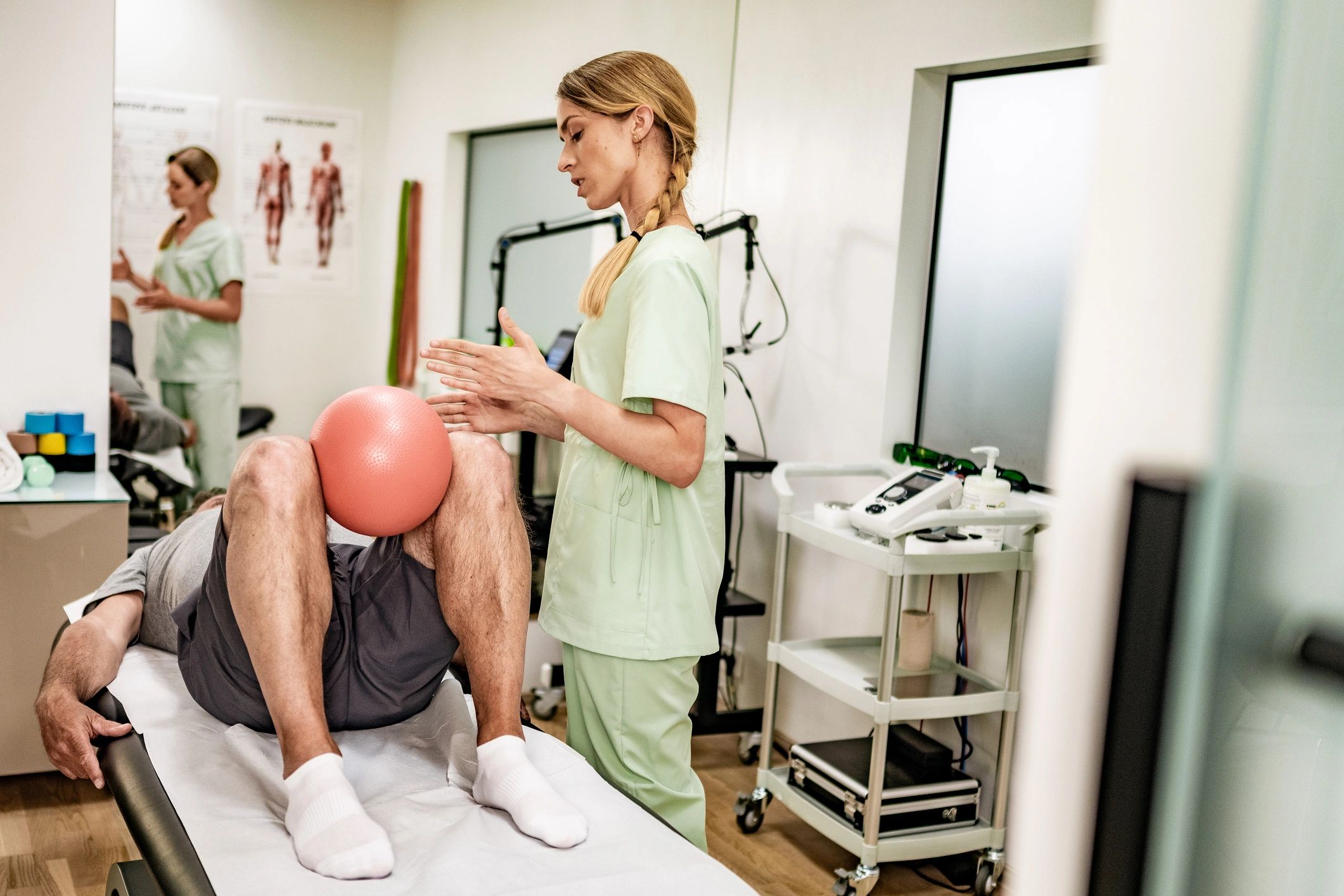 Terapeuta asistiendo ejercicio de rehabilitación con balón en clínica